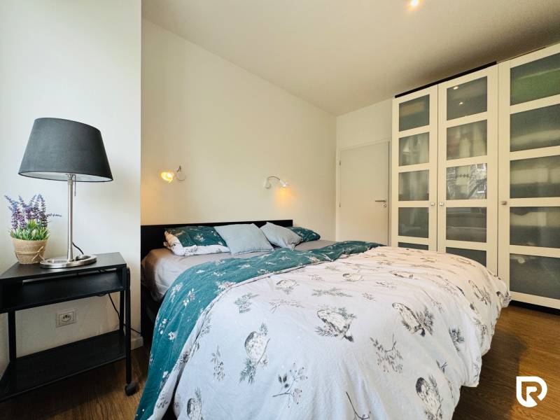 Tichý 2i byt v TOP Lokalite Nív | Trenčianska, BA - Spálňa s pohodlnou posteľou a skriňou v 2-izbovom byte s podlahou s dreveným dekorom.