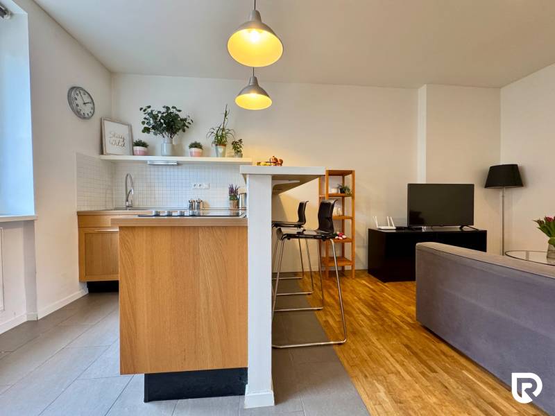 Tichý 2i byt v TOP Lokalite Nív | Trenčianska, BA - Kuchyňa a obývacia izba v 2-izbovom byte s podlahou s dreveným dekorom.