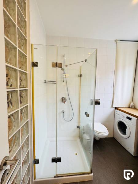 Tichý 2i byt v TOP Lokalite Nív | Trenčianska, BA - Kúpeľňa v 2-izbovom byte s preskleným sprchovým kútom a práčkou.