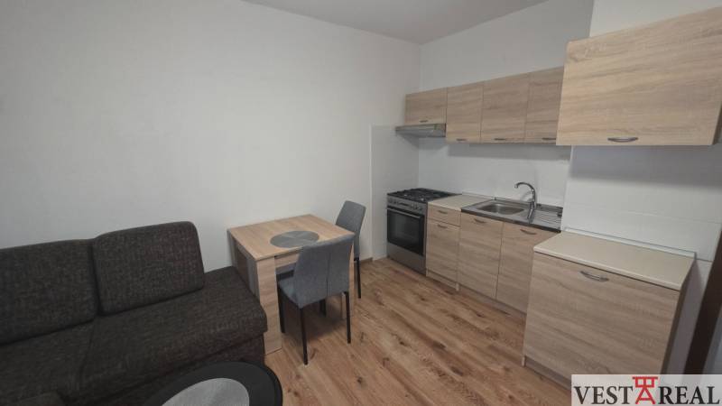 Prenájom veľký 1 izbový byt 48m2 Vráble- Centrum - Kuchyňa v 1-izbovom byte s dreveným dekorom podlahy a nábytku.