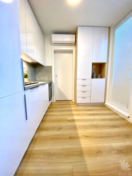 Dizajnový moderný 2 izbový byt Jurigovo nám. Bratislava IV Karlova Ves - Kuchyňa s bielymi skrinkami a podlahou s dreveným dekorom v 2-izbovom byte.