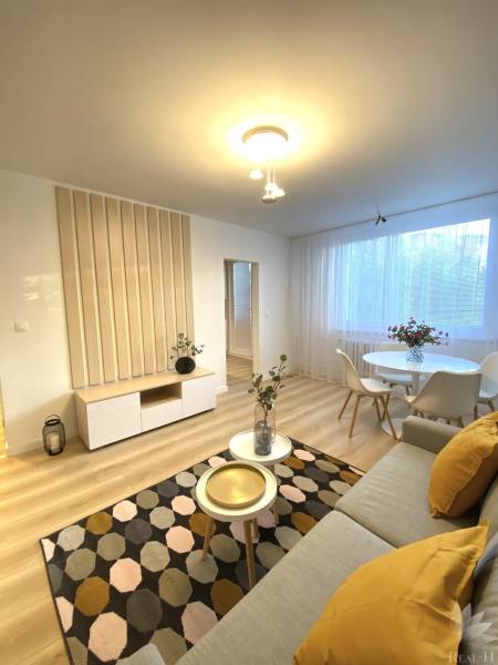 Dizajnový moderný 2 izbový byt Jurigovo nám. Bratislava IV Karlova Ves - Obývacia izba 2-izbového bytu s podlahou s dreveným dekorom, svetlým nábytkom a dekoráciami.
