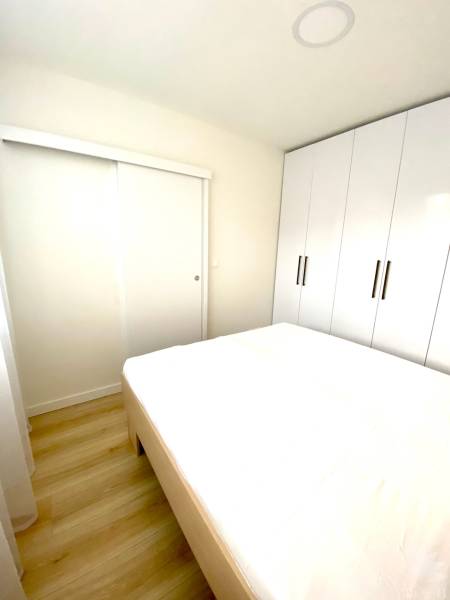 Dizajnový moderný 2 izbový byt Jurigovo nám. Bratislava IV Karlova Ves - Spálňa v 2-izbovom byte s posteľou a veľkou vstavanou skriňou.