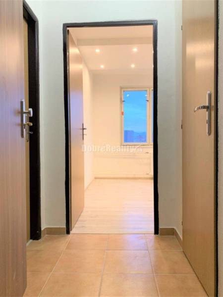 Nový nájomné 1 izbové byty v Prievidzi - ihneď k dispozícii - Chodba s keramickou dlažbou a vstupom do izby s podlahou s dreveným dekorom.