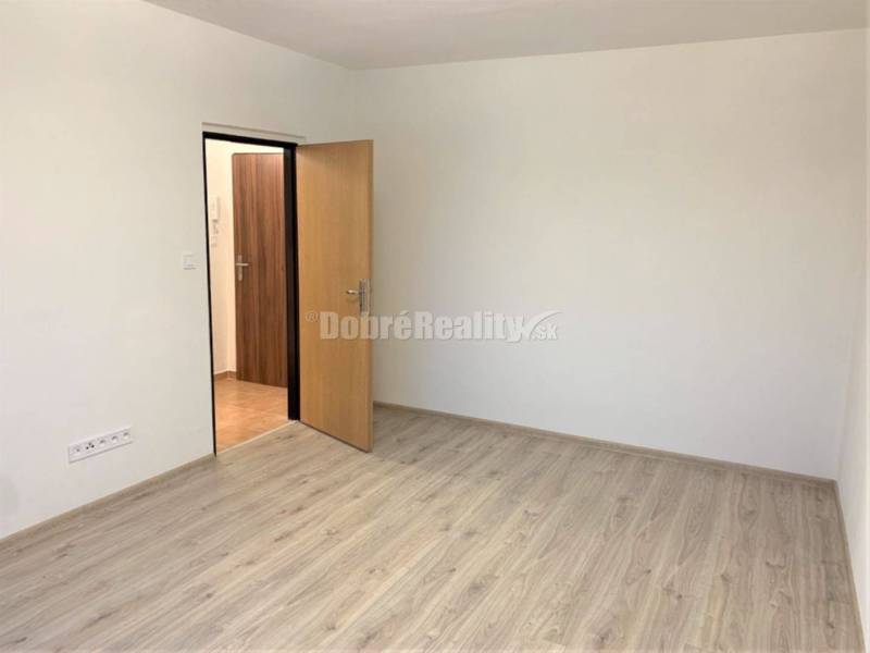 Nový nájomné 1 izbové byty v Prievidzi - ihneď k dispozícii - Izba v 1-izbovom byte s bielymi stenami a podlahou s dreveným dekorom.