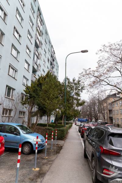 Predaj 4 izbový byt v TOP lokalite Ondavská ulica  BA II Ružinov- Nivy - Viacposchodový bytový dom na Ondavskej ulici v Bratislave - Nivy, obklopený autami a stromami.