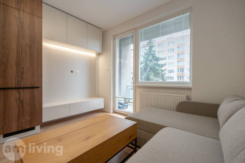 KOMPLETNÁ REKONŠTRUKCIA- 3i 54 m² + balkón - Dubnica nad Váhom - Obývačka v 3-izbovom byte s podlahou s dreveným dekorom, sedačkou a nábytkom.