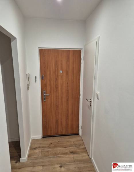Prenájom 2-izbového bytu Bratislava II, Ružinov - Vstupná chodba v 2-izbovom byte s drevenými podlahami a bielymi stenami.
