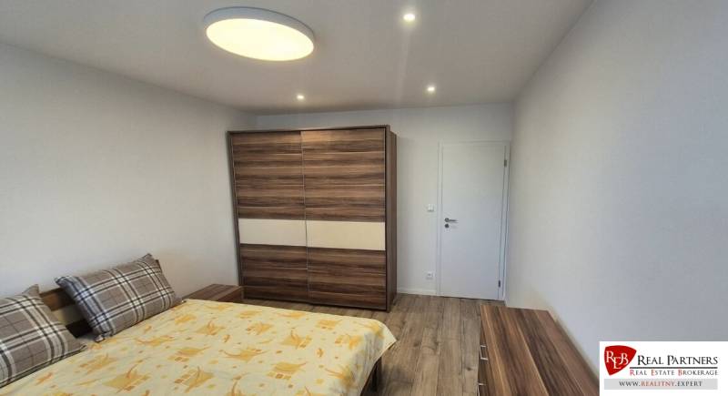 Prenájom 2-izbového bytu Bratislava II, Ružinov - Spálňa v 2-izbovom byte s podlahou s dreveným dekorom a veľkou skriňou.