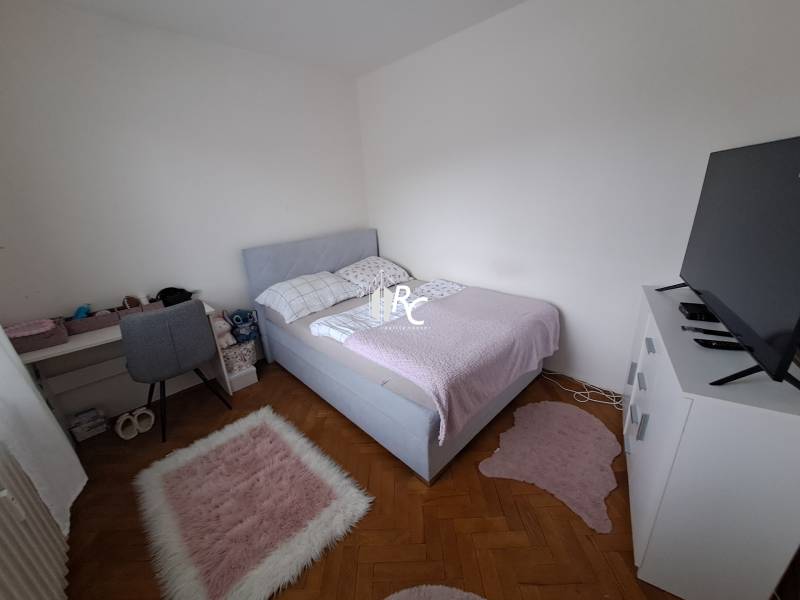 Predaj čiastočne prerobený 3 izbový byt Martin Sever - Spálňa v 3-izbovom byte s podlahou s dreveným dekorom, posteľou a televízorom na skrinke.