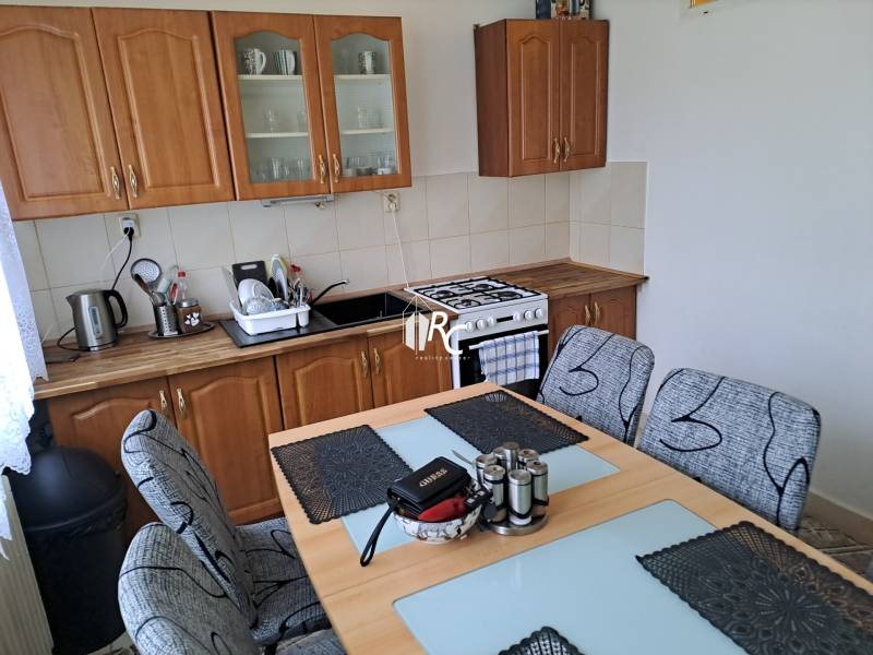 Predaj čiastočne prerobený 3 izbový byt Martin Sever - Kuchyňa s jedálenským stolom v 3-izbovom byte, drevené skrinky a sporák.