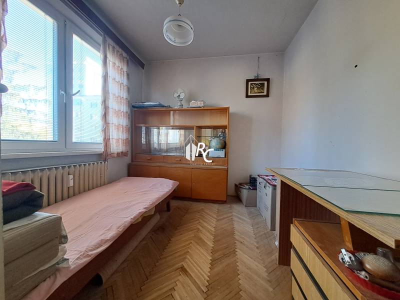 Centrum Martina slnečný 3-izbový byt s balkónom a potenciálom - Malá izba so sedačkou a vitrínou v 3-izbovom byte, podlaha s dreveným dekorom.
