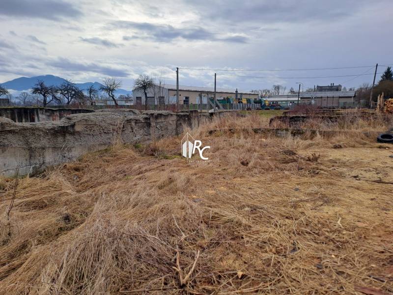 Stavebný pozemok 2 375 m² v obci Valča  - Pozemky na bývanie vo Valči s výhľadom na hory a starou budovou v diaľke.