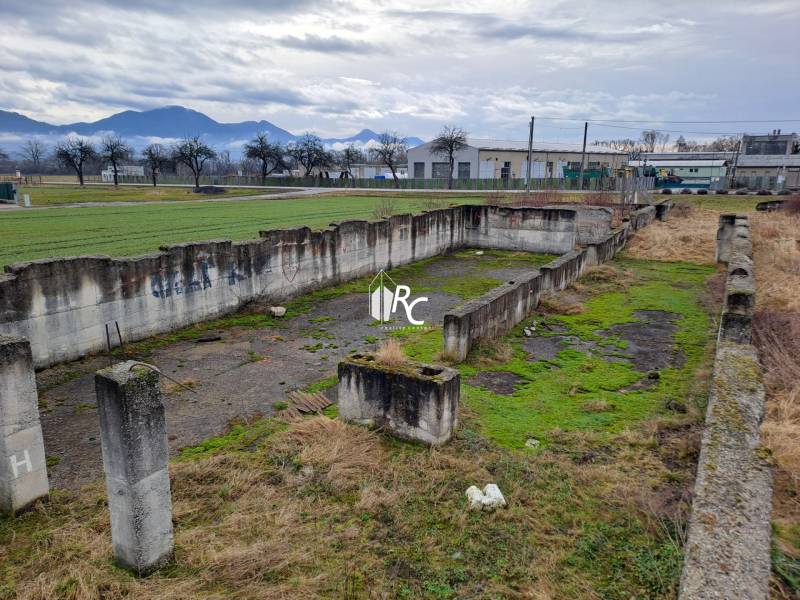 Stavebný pozemok 2 375 m² v obci Valča  - Opustené betónové základy na pozemkoch na bývanie v obci Valča s výhľadom na kopce.