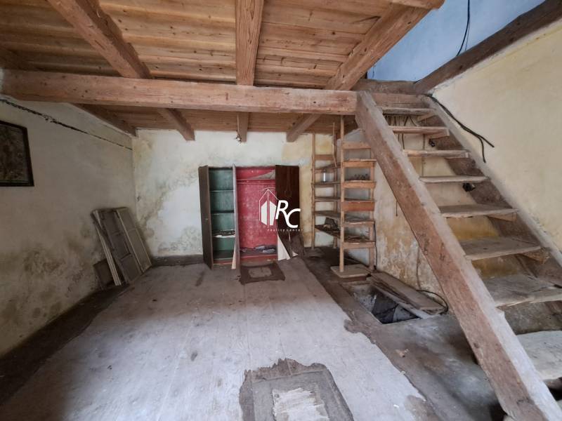 Rodinný dom v obci Háj v pôvodnom stave s veľkým potenciálom - Interiér rodinného domu s dreveným schodiskom a podlahou s dreveným dekorom.
