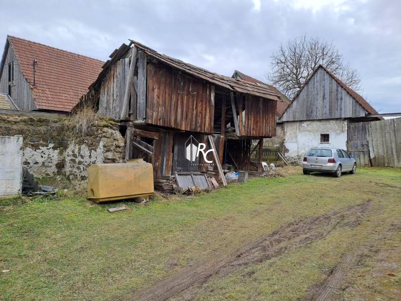 Rodinný dom v obci Háj v pôvodnom stave s veľkým potenciálom - Rodinný dom v Háji s drevenou hospodárskou budovou a zaparkovaným autom na tráve.