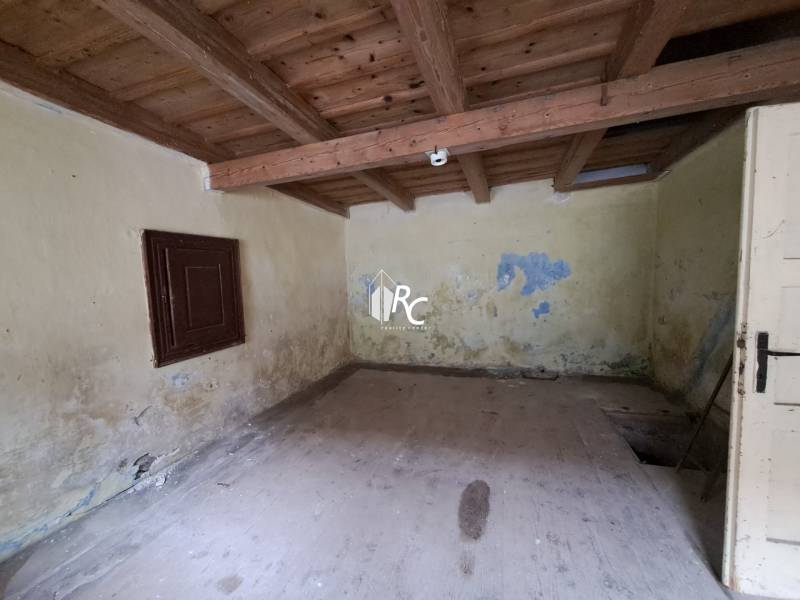 Rodinný dom v obci Háj v pôvodnom stave s veľkým potenciálom - Miestnosť v rodinnom dome s dreveným stropom a opotrebovanými stenami.