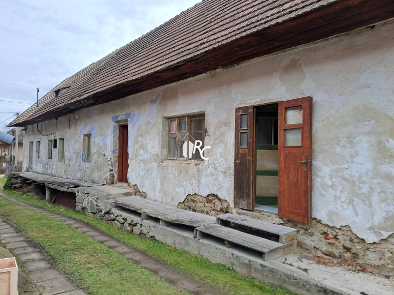 Rodinný dom v obci Háj v pôvodnom stave s veľkým potenciálom - Rodinný dom v Háji s poškodenou fasádou a drevenými detailami na terase.