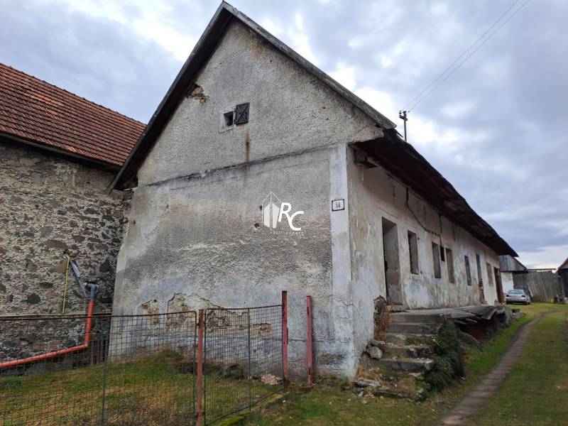 Rodinný dom v obci Háj v pôvodnom stave s veľkým potenciálom - Záber staršieho rodinného domu v Háji so schodmi a záhradou, obloha zachmúrená.