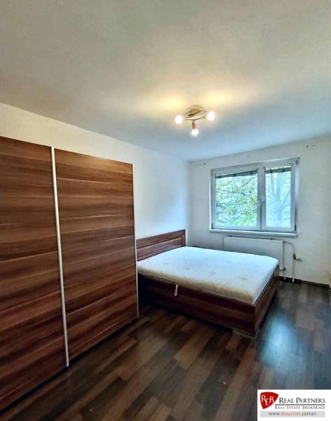 Predaj 4-izbového bytu na začiatku Petržalky Bratislava V - Spálňa so skriňou, posteľou a podlahou s dreveným dekorom v 4-izbovom byte.