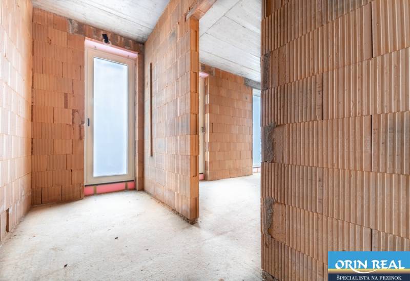 ATRAKTÍVNA MODERNÁ 5 IZB.ROZOSTAVANÁ VILA na KOLIBE - Nedokončený interiér rodinného domu s betónovou podlahou a sklenenými dverami.