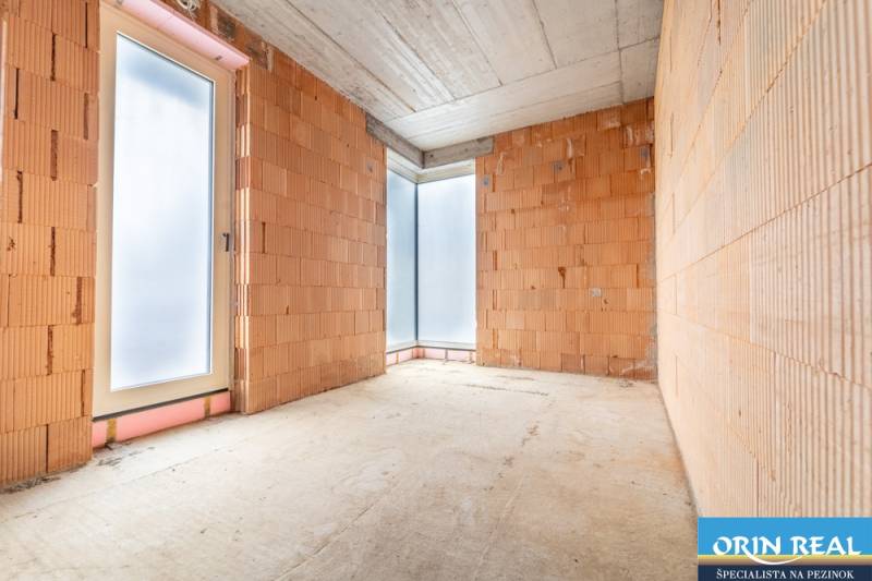 ATRAKTÍVNA MODERNÁ 5 IZB.ROZOSTAVANÁ VILA na KOLIBE - Miestnosť s nedokončenými tehlovými stenami a veľkými oknami v rodinnom dome.