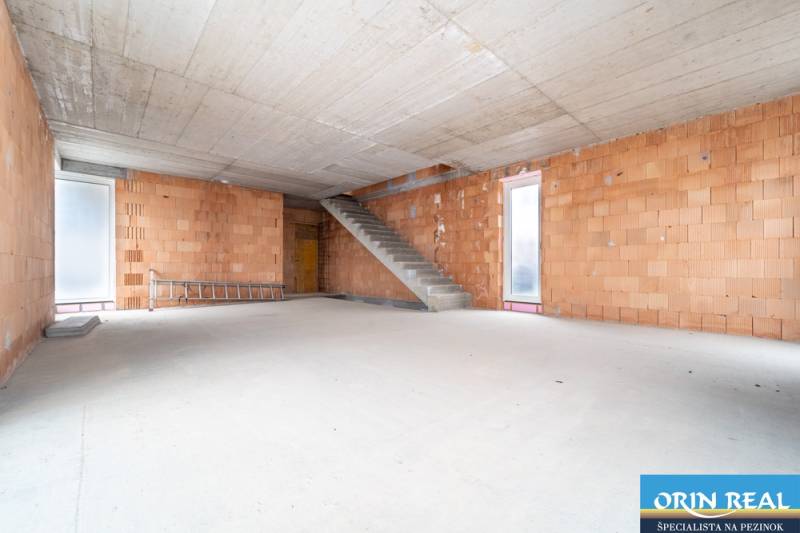 ATRAKTÍVNA MODERNÁ 5 IZB.ROZOSTAVANÁ VILA na KOLIBE - Priestranný interiér rodinného domu s neomietnutými tehlovými stenami a betónovým schodiskom.