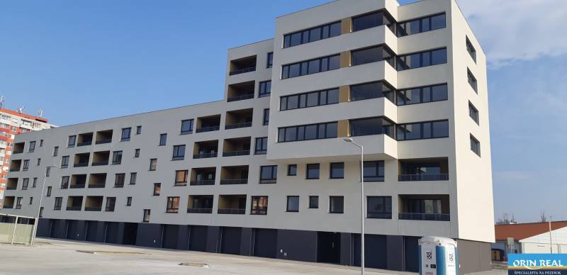 KÚPA GARÁŽE V PEZINKU - Budova s garážami na ulici Dona Sandtnera v Pezinku, svetlá fasáda s tmavými oknami.