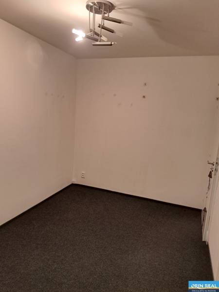 PREDAJ NEBYTOVÉHO PRIESTORU TAKMER V CENTRE PEZINKA - Prázdna miestnosť s kobercom a osvetlením, ideálna pre kancelárie na ulici Hrnčiarska.