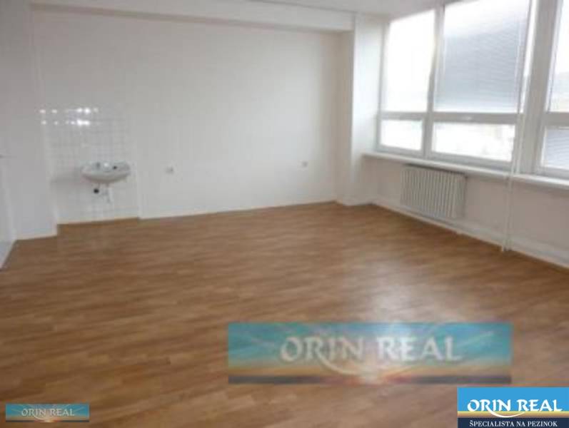 PRENÁJOM KANCELÁRSKÝCH PRIESTOROV NA RAČIANSKEJ ULICI - Prázdna miestnosť s umývadlom, drevená podlaha, veľké okná na ulici Račianska.