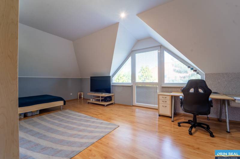 ,,,EXKLUZÍVNE,,,PREDAJ PRIESTRANNÉHO 5 IZB.RD V PEZINKU / LIMBACH - Podkrovná izba v rodinnom dome so stolom, posteľou a televízorom.