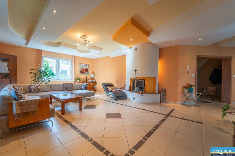 ,,,EXKLUZÍVNE,,,PREDAJ PRIESTRANNÉHO 5 IZB.RD V PEZINKU / LIMBACH - Obývačka rodinného domu so sedačkou, krbom a rastlinami na podlahe.