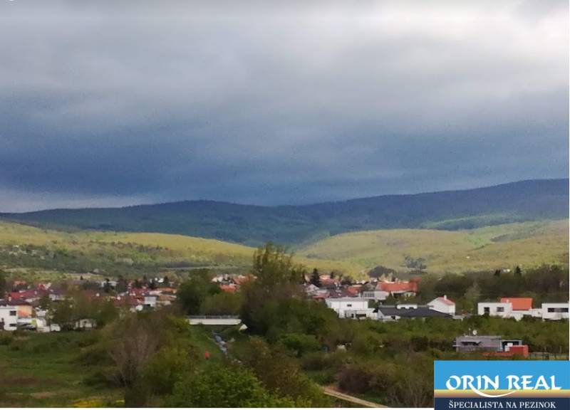 PREDAJ PRIESTRANNÉHO 3 IZB. BYTU V NOVOSTAVBE V PEZINKU-DONA SANDTNERA - Pohľad na Pezinok: domy, kopce a zeleň s výhľadom na ulici Dona Sandtnera.