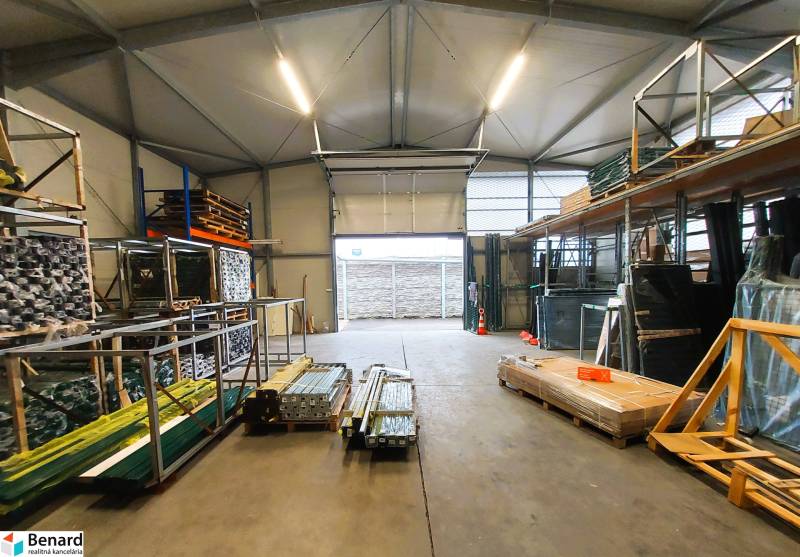 PRENÁJOM: Moderná hala (525 m²) v TOP lokalite Žiliny – Kamenná ul. - Obchodné priestory s uskladneným materiálom a otvorenou bránou, podlaha má betónový povrch.