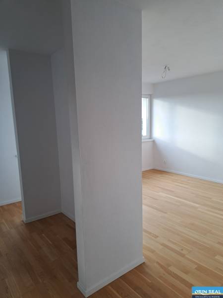 PREDAJ NADŠTANDARDNÉHO 4 IZB.BYTU V NOVOM KOMPLEXE-VINICE-150,18 m2 - Interiér 4-izbového bytu s drevenými podlahami a bielymi stenami na ulici Obchodná.
