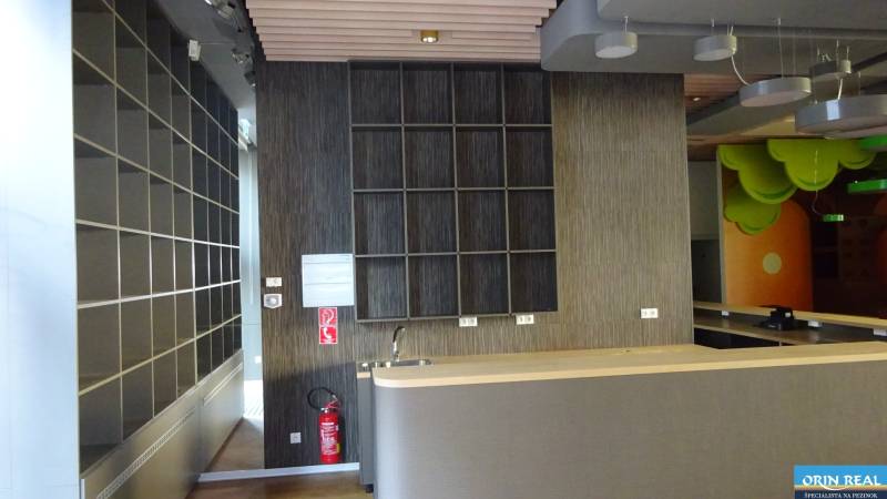 PRENÁJOM NEB.PRIESTORU V POLYFUNKČNOM DOME V CENTRE PEZINKA - Interiér obchodných priestorov na ulici Moyzesova s regálmi a pultom.