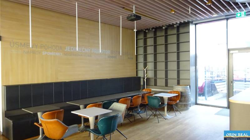 PRENÁJOM NEB.PRIESTORU V POLYFUNKČNOM DOME V CENTRE PEZINKA - Interiér bistra na ulici Moyzesova, s farebnými stoličkami a dekoratívnym drevom. Obchodné priestory.