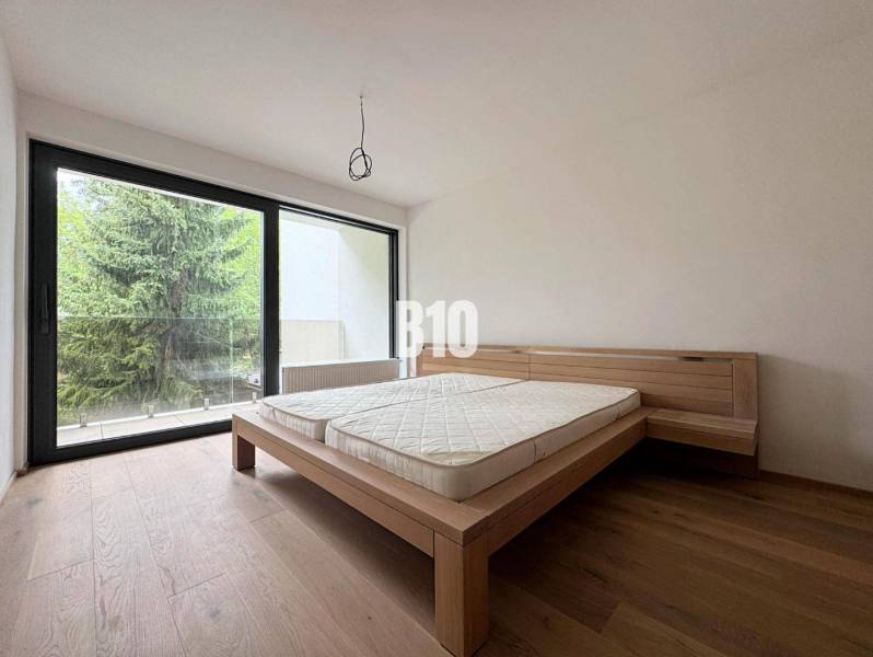 Posledný voľný APARTMÁN na kľúč - Rajecké Teplice - Spálňa v 2-izbovom byte s drevenou podlahou a veľkým oknom na terasu.