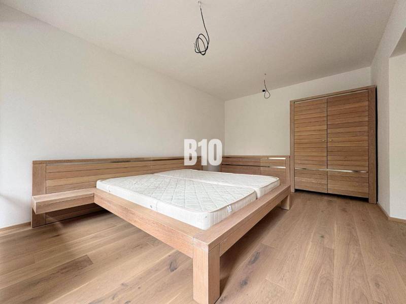 Posledný voľný APARTMÁN na kľúč - Rajecké Teplice - Spálňa v 2-izbovom byte s drevenou posteľou a skriňou na drevenej podlahe.