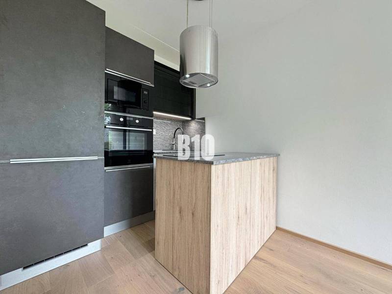 Posledný voľný APARTMÁN na kľúč - Rajecké Teplice - Moderná kuchyňa v 2-izbovom byte s drevenou podlahou a tmavou skriňou.