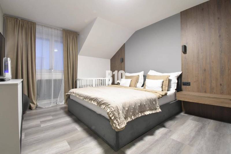 Moderný kompletne zrekonštruovaný Mezonet - centrum mesta - Svetlá spálňa s pohodlnou posteľou v 4-izbovom byte, podlaha s dreveným dekorom.