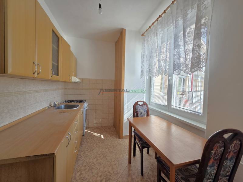 Predaj - 3 izbový byt,  69 m2, balkón,  ul.ČSA, KE - Staré Mesto - Kuchyňa s drevenými skrinkami, stolom a dvomi stoličkami v 3-izbovom byte.