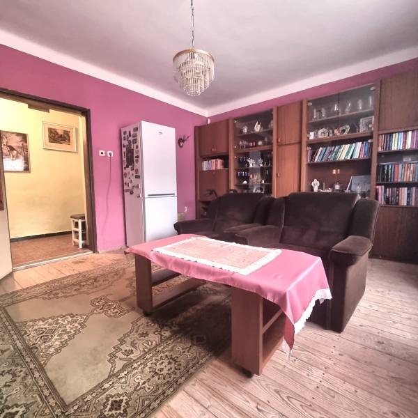 Rodinný dom na predaj - Znížená cena. - Obývačka rodinného domu s ružovými stenami, podlahou s dreveným dekorom a knižnicou.