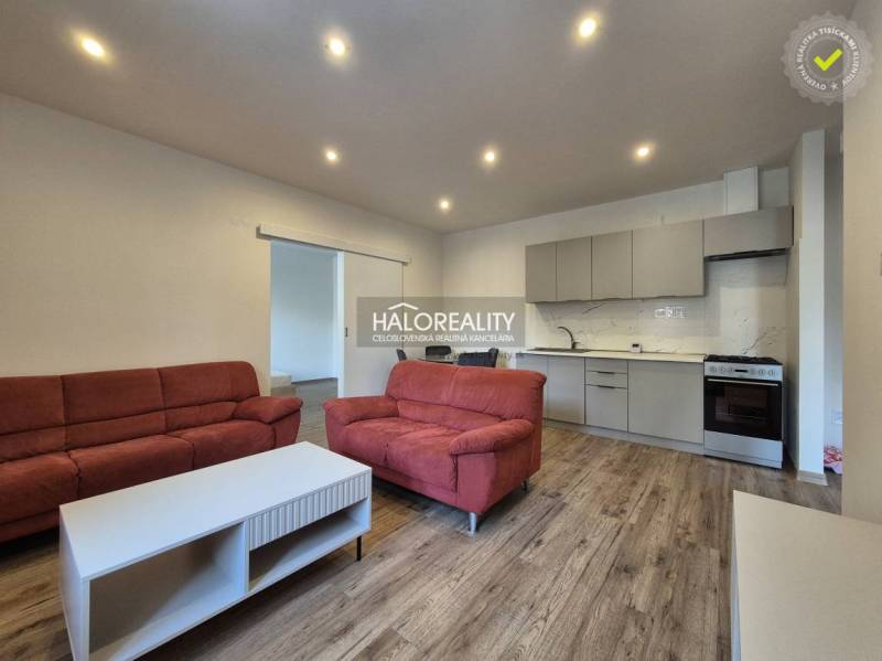 REZERVOVANÉ - Predaj, dvojizbový byt Lučenec - EXKLU... - Obývačka v 2-izbovom byte s podlahou s dreveným dekorom, červené sedačky, kuchyňa.