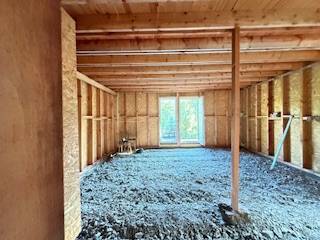 Chata pred dokončením, pozemok 770 m2, Horná Maríková - Rozostavaný interiér chaty s drevenou konštrukciou a otvorom na terasu.
