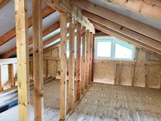 Chata pred dokončením, pozemok 770 m2, Horná Maríková - Podkrovie s oknom, drevenými trámami a podlahou s dreveným dekorom v chate.