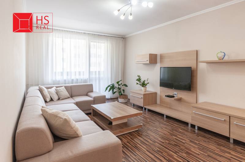 Predaj 3i bytu 84m2 - dva balkóny , Nábrežná v NZ - Obývacia izba v 3-izbovom byte s pohovkou, televízorom a podlahou s dreveným dekorom.