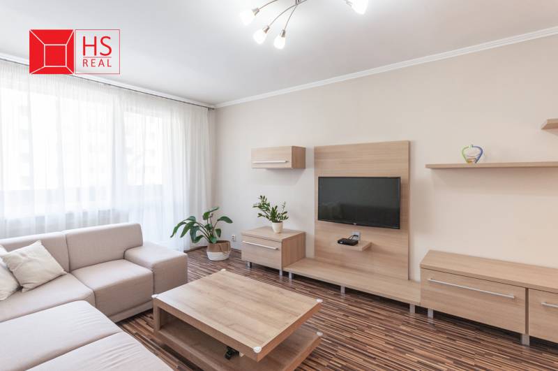 Predaj 3i bytu 84m2 - dva balkóny , Nábrežná v NZ - Obývačka 3-izbového bytu s podlahou s dreveným dekorom a pohodlnou sedačkou.