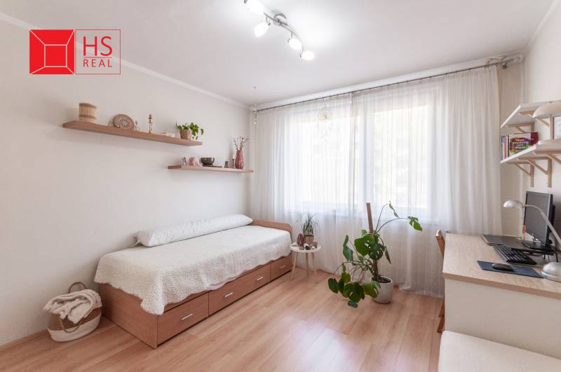 Predaj 3i bytu 84m2 - dva balkóny , Nábrežná v NZ - Svetlá izba s posteľou, písacím stolom a podlahou s dreveným dekorom v 3-izbovom byte.