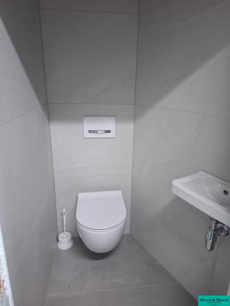 Moderný rodinný dom so záhradou, bazénom a nadštandardným priestorom - Kúpeľňa v rodinnom dome s toaletou, umývadlom a bielymi obkladačkami.